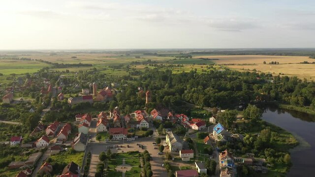 Aerial: The restored facades of the Zheleznodorozhny town on the background of an abandoned old Prussian church, Russia