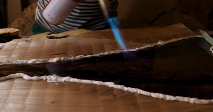 Closeup carpenter removing air bubbles with blowtorch from epoxy table