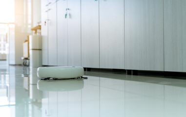Robot vacuum cleaner cleaning floor in office. White robot vacuum cleaner for the smart home...
