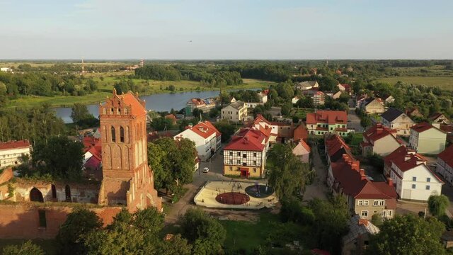 Aerial: The restored facades of the Zheleznodorozhny town on the background of an abandoned old Prussian church, Russia