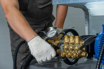A man's hand in a white glove turns on a set with a pressure gauge for testing high pressure...