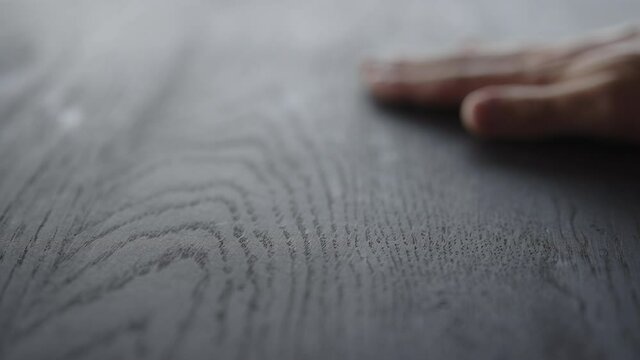 Slow motion man hand touches black oak table surface