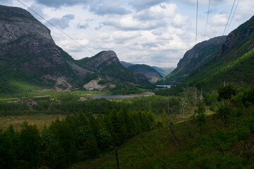 Fototapeta na wymiar Power Lines running over rural mountains in Europe (Norway), with fjords in background - Green Future concept