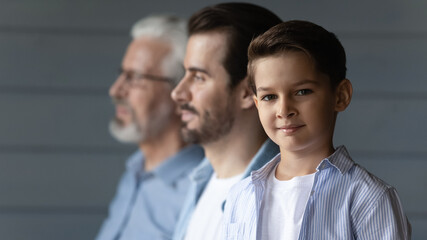 Portrait of happy small teen boy look at camera pose on grey wall background with young Caucasian...