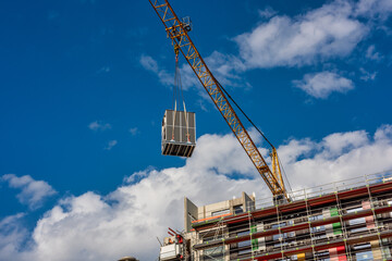 Crane lifting a wooden building module to its position in the structure. Construction site of an...