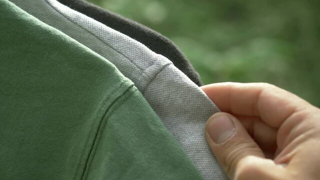 colorful organic cotton t shirts on hangers outdoor. sustainable fashion concept (eco fashion). textile and fashion industries, environmental problems, recycling, synthetic agricultural chemicals