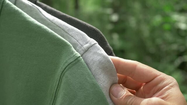 colorful organic cotton t shirts on hangers outdoor. sustainable fashion concept (eco fashion). textile and fashion industries, environmental problems, recycling, synthetic agricultural chemicals