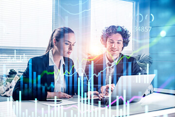 Businessman and businesswoman working on laptop analyzing stock market behavior