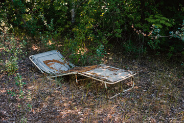 old sun lounger forgotten in a forest. An old beach chair left behind in the woods.