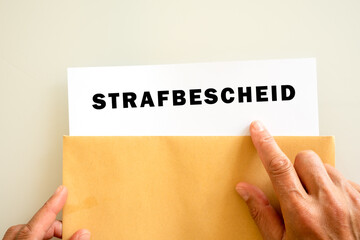 Briefumschlag mit einem Strafbescheid der geöffnet wird von einer Hand