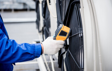 Technician uses a thermal imaging infrared thermometer to check the condensing unit heat exchanger.