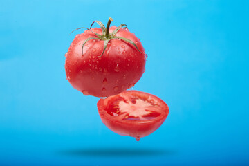A ripe tomato cut in the air on a blue background