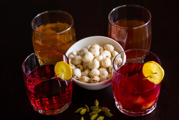 Flat lay,close up view of crunchy Fox Nuts also called Makhana or Makhane.Served with Sangria fruit punch made from Kokam juice,Kashmiri Kahwa green tea on dark background.Indian and spanish drink.