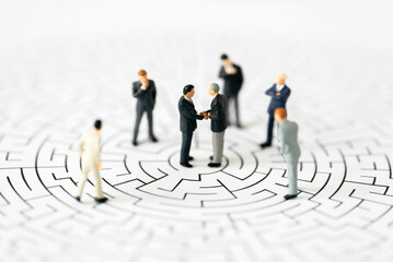 Miniature business people man shake hand partner client customers on center of maze with success...