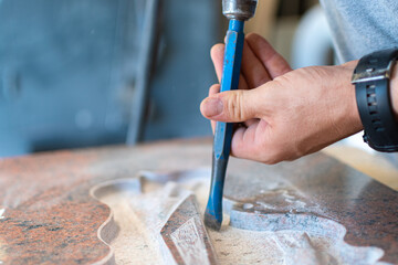 Caucasian man hands bushhammered a tombstone in a workshop,