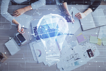 Double exposure of woman hands working on computer and light bulb hologram drawing. Top View. Idea concept.