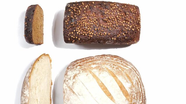Top view collection of different fresh bakery breads with seeds, coriander, brioche, rye, with cut loaf slices