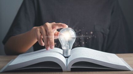 Idea, Self learning, Education knowledge, Studying concept. Hand touch light bulb or lamp on textbook thinking ideas or new ideas futuristic.
