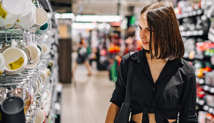 Shopping yong woman looking at the shelves with cup in supermarket. 