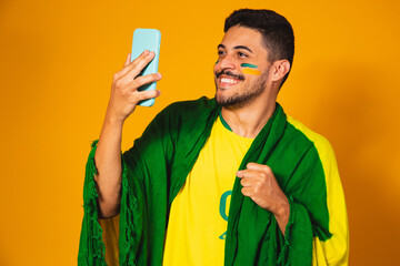 Brazilian supporter watching the game of brazil by cell phone and celebrating the goal