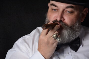 Portrait of a man with a cigar and a beard in a dark room