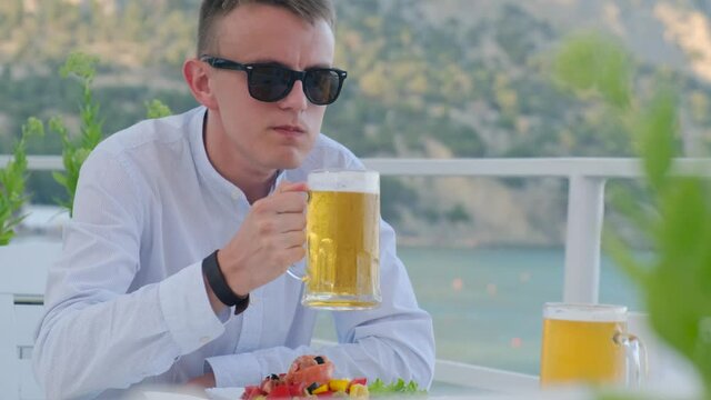 Satisfied man drinks beer at this cafe with vim on the sea