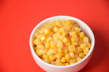 Bowl of sweet corn in white bowl  on red background