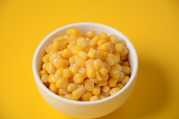 Bowl of sweet corn in white bowl  on yellow background