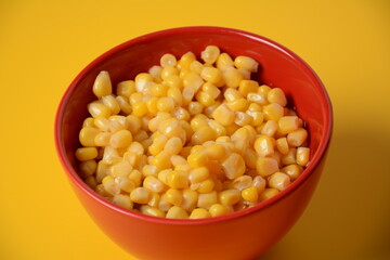Bowl of sweet corn in red bowl  on yellow background
