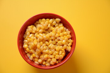 Bowl of sweet corn in red bowl  on yellow background