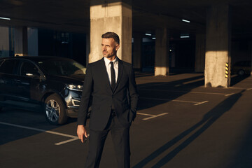 Confident mature man in full suit walking by parking lot © gstockstudio