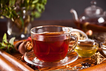 Cup of herbal tea with small bowl with honey on the tray.