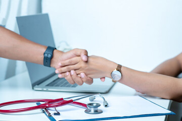 The doctor holds the patient's arm and diagnoses the disease on a white table. There is a stethoscope and recording paper in the office at the hospital.