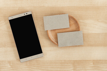 Blank business cards and tablet on wooden office table. Recycled paper. Business card and cell phone Mock Up.