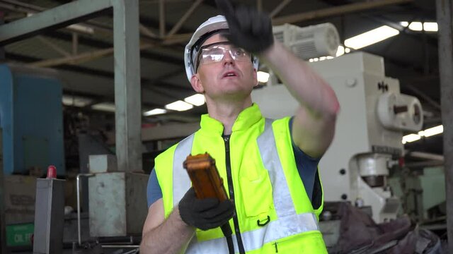 Engineer technician manager   controlling by remote control with heavy machine in the industrial plant while the workers are working in Industrial factory .