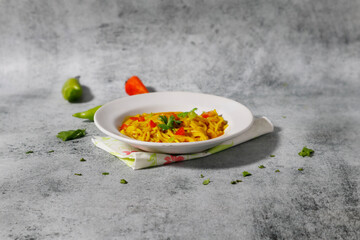 Vegetarian Noodles plate with coriander, green chili and tomatoes on grey background. Side view with copy space.