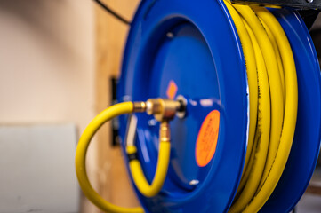 auto-rewinding air hose reel with coiled tubing mounted on a wall in a shop - Powered by Adobe