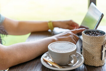 Hot Cappuccino coffee for quarantined woman wear face mask and work from home by using tablet and stress relief with hot coffee. Concepts of Covid-19 (Coronavirus disease). Selective focus on coffee.