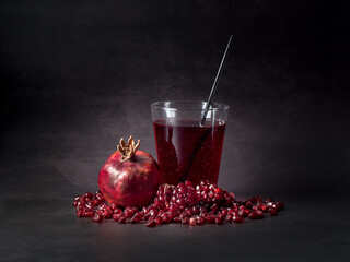 Pomegranate juice in a glass and pomegranate fruit on  black background.