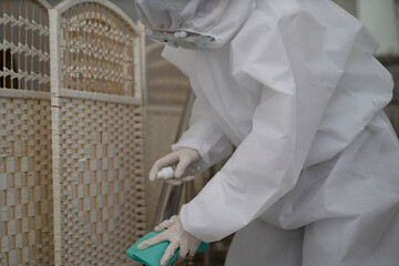 Worker in protective suit disinfecting house to prevent Coronavirus