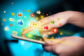 Close-up of a hand using tablet with social media icons