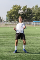 The boy loves to play football, trains with the ball on the artificial turf and scores a goal. The boy plays football