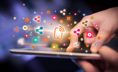 Close-up of a hand using tablet with social media icons