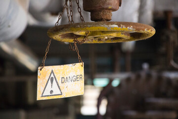 Danger sign hanging besides a large valve handle wheel