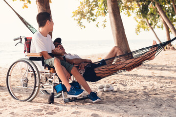 Asian special child on wheelchair is happily on the beach with parents in family holiday to travel and learning about nature around the sea beach,Life in the education age,Happy disabled kid concept