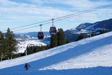 OBERSTAUFEN, GERMANY - 31 DEC, 2017: Ski lift with gondola and ski slope and skiers in the foreground