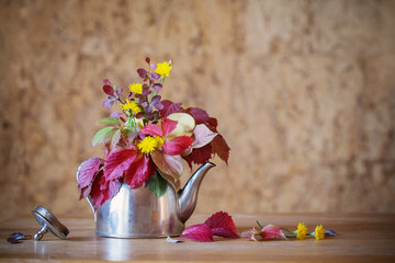 autumn bouquet in iron teapot on wooden table