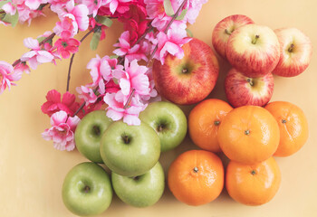 Apples and Orange fruit putat the right side of pink flowers