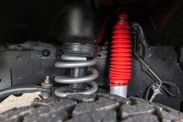 Off-road car chassis with a detailed view of the coil spring at the front wheel.