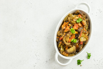 Healthy vegan dinner vegetable saute in baking dish. Space for text, top view